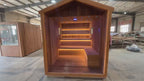 4 - person modern outdoor dry - steam sauna room. It features a square cube design and is made of red cedar, spruce, and hemlock. It is electrically powered.